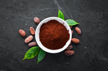 Bir kase ve kakao fasulyesinde kakao tozu. Siyah bir arka plan üzerinde. Üst te. Ücretsiz kopyalama alanı.