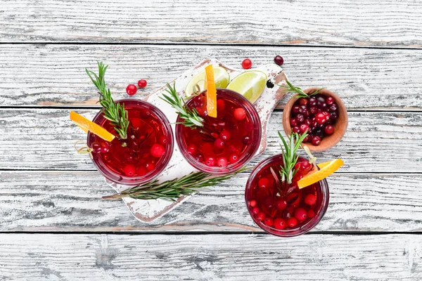 Glasses with cranberry juice. Cranberries, limes, rosemary. On a rustic background. Top view. Free space for your text.