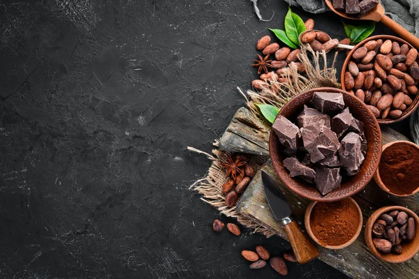 Cocoa beans, chocolate, cocoa butter and cocoa powder on a black background. Top view. Free copy space.