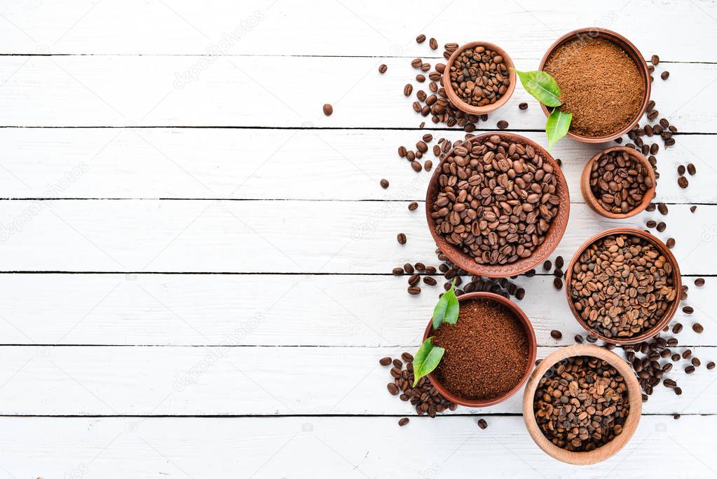 Ground coffee and coffee beans. On a white wooden background. Top view. Free space for your text.