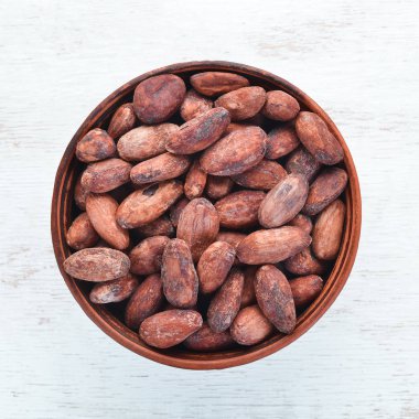 Beyaz ahşap arka plan üzerinde bir kase kakao çekirdekleri. Üst te. Ücretsiz kopyalama alanı.