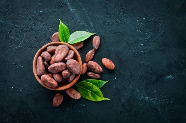 Siyah bir arka plan üzerinde bir kase kakao çekirdekleri. Üst te. Ücretsiz kopyalama alanı.