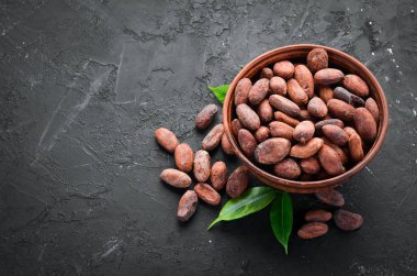 Siyah bir arka plan üzerinde bir kase kakao çekirdekleri. Üst te. Ücretsiz kopyalama alanı.
