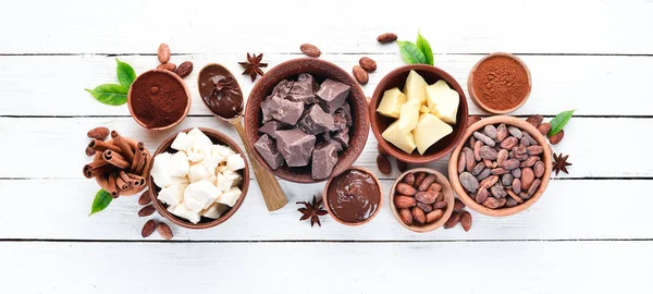 Cocoa beans, chocolate, cocoa butter and cocoa powder on a white wooden background. Top view. Free copy space.