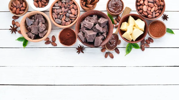 Cocoa beans, chocolate, cocoa butter and cocoa powder on a white wooden background. Top view. Free copy space.