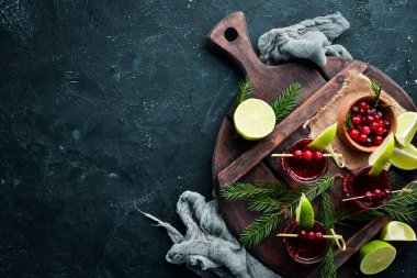 Bardaktaki kızılcıktan alkollü likörü. Kızılcık, limon, biberiye. Rustik bir arka planda. Üst te. Metniniz için boş alan.