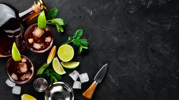 Alcoholic Beverage Rum, lime and mint on a black stone background. Top view. Free space for your text.