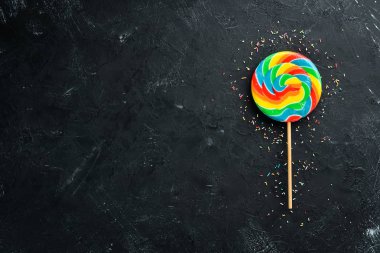 Karamel şekerler ve lolipoplar. Renkli şekerler. Siyah bir arka plan üzerinde. Üst te. ücretsiz kopyalama alanı.