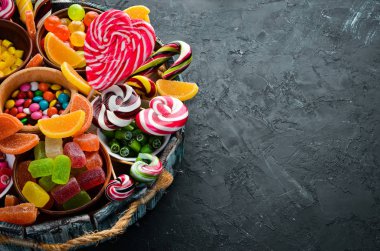 Renkli şekerler ve lolipoplar. Siyah taş bir arka plan üzerinde. Üst te. ücretsiz kopyalama alanı.