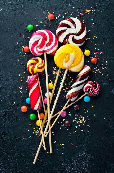 Colorful candies and lollipops. On a black stone background. Top view. free copying space.