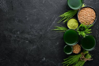 Yeşil filizlenmiş buğday ve buğday tanelerinin suyu. Siyah bir arka plan üzerinde. Mikro Yeşil. Sağlıklı yiyecekler. Üst te. Metniniz için boş alan.