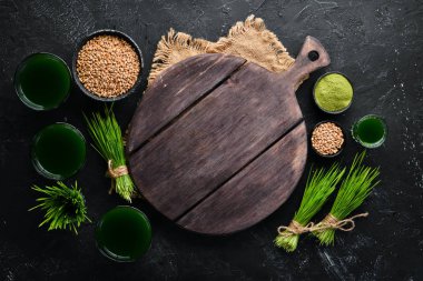 Yeşil filizlenmiş buğday ve buğday tanelerinin suyu. Siyah bir arka plan üzerinde. Mikro Yeşil. Sağlıklı yiyecekler. Üst te. Metniniz için boş alan.