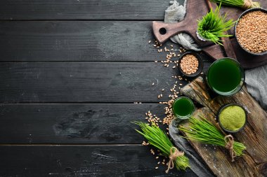 Yeşil filizlenmiş buğday ve buğday tanelerinin suyu. Siyah bir arka plan üzerinde. Mikro Yeşil. Sağlıklı yiyecekler. Üst te. Metniniz için boş alan.