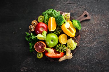 C vitamini içeren gıdalar: Portakal, limon, elma, gül, sarımsak, brokoli, elma, kivi, ıspanak. Üst te. Kahverengi arka planda.