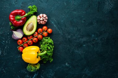 Siyah bir arka plan üzerinde taze sebze. Avokado, domates, sarımsak, maydanoz, kırmızı biber. Üst te. Metniniz için boş alan.