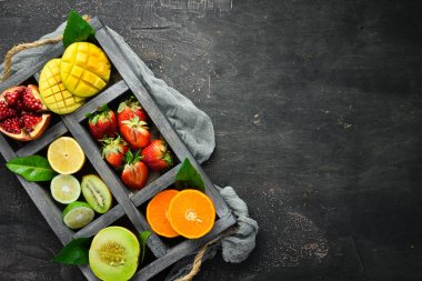 Tahta bir kutuda meyveler. Narenciye, kavun, nar, çilek, muz. Üst te. Metniniz için boş alan.