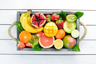 Tahta bir kutuda meyveler. Narenciye, kavun, nar, çilek, muz. Üst te. Metniniz için boş alan.