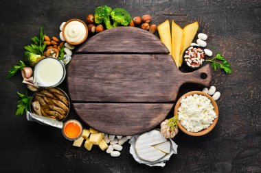 Kalsiyum açısından zengin ürün grubu. Sağlıklı diyet gıda: peynir, süt, parmesan, ekşi krema, balık, badem, maydanoz, sarımsak, brokoli. Eski arka planda. Üst te. Ücretsiz kopyalama alanı.