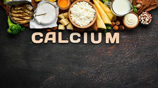 Group of products rich in calcium. Healthy diet food: cheese, milk, parmesan, sour cream, fish, almonds, parsley, garlic, broccoli. On the old background. Top view. Free copy space.