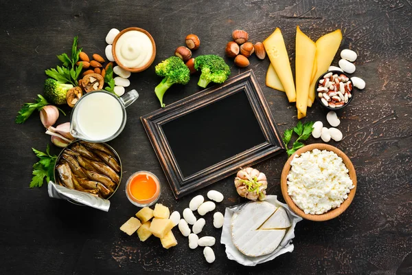 Kalsiyum açısından zengin ürün grubu. Sağlıklı diyet gıda: peynir, süt, parmesan, ekşi krema, balık, badem, maydanoz, sarımsak, brokoli. Eski arka planda. Üst te. Ücretsiz kopyalama alanı.