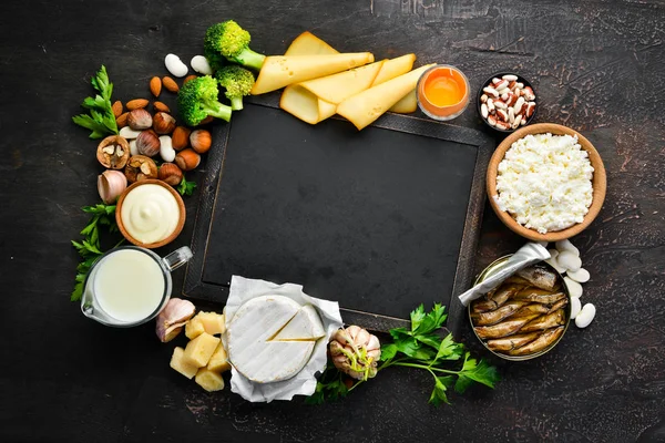 Kalsiyum açısından zengin ürün grubu. Sağlıklı diyet gıda: peynir, süt, parmesan, ekşi krema, balık, badem, maydanoz, sarımsak, brokoli. Eski arka planda. Üst te. Ücretsiz kopyalama alanı.