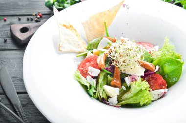 Brie peynir, kiraz domates ve ıspanak ile sebze salatası. Tabakta. Üst te. Metniniz için boş alan. Rustik stil.