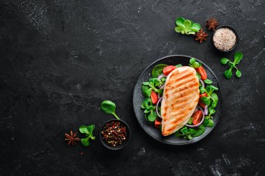 Sebzeli fırında tavuk filetosu. Ahşap arka plan üst görünümünde siyah bir tabak ta. Metniniz için boş alan. Düz yatıyordu