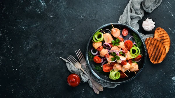 Chicken kebab with vegetables. Kebab in a black plate. Top view. Free copy space.