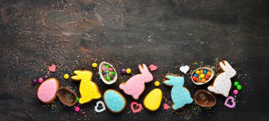 Paskalya arka plan tebrik. Paskalya zencefilli kurabiye ve dekoratif renkli yumurta. Kahverengi bir arka plan üzerinde. Üst te. ücretsiz kopyalama alanı.