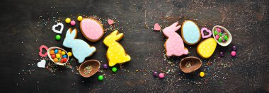 Paskalya arka plan tebrik. Paskalya zencefilli kurabiye ve dekoratif renkli yumurta. Kahverengi bir arka plan üzerinde. Üst te. ücretsiz kopyalama alanı.