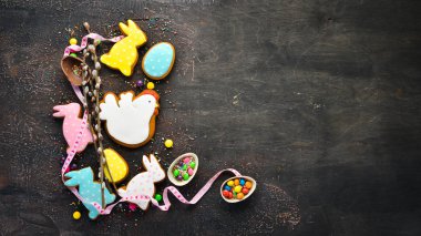 Paskalya arka plan tebrik. Paskalya zencefilli kurabiye ve dekoratif renkli yumurta. Kahverengi bir arka plan üzerinde. Üst te. ücretsiz kopyalama alanı.