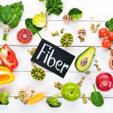 Doğal lif içeren gıdalar: avokado, kivi, elma, domates, ıspanak, kırmızı biber, portakal, limon. Üst te. Metniniz için boş alan. Beyaz arka planda.