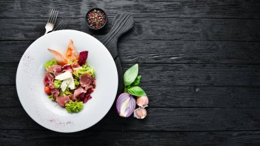 Brie peynirve prosciutto ile sebze salatası. Tabakta. Üst te. Metniniz için boş alan. Rustik stil.