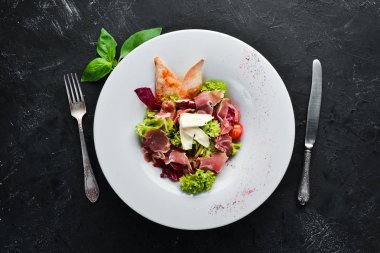 Brie peynirve prosciutto ile sebze salatası. Tabakta. Üst te. Metniniz için boş alan. Rustik stil.