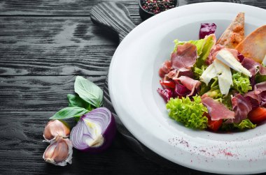 Brie peynirve prosciutto ile sebze salatası. Tabakta. Üst te. Metniniz için boş alan. Rustik stil.