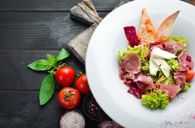 Brie peynirve prosciutto ile sebze salatası. Tabakta. Üst te. Metniniz için boş alan. Rustik stil.