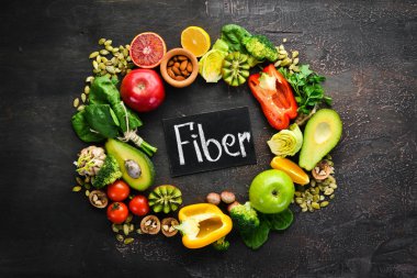 Doğal lif içeren gıdalar: avokado, kivi, elma, domates, ıspanak, kırmızı biber, portakal, limon. Üst te. Metniniz için boş alan. Kahverengi arka planda.