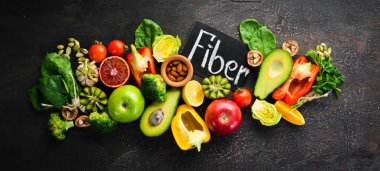 Doğal lif içeren gıdalar: avokado, kivi, elma, domates, ıspanak, kırmızı biber, portakal, limon. Üst te. Metniniz için boş alan. Kahverengi arka planda.