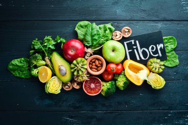 Lif içeren meyve ve sebzeler: Avokado, kivi, elma, domates, ıspanak, kırmızı biber, portakal, limon. Üst te. Metniniz için boş alan. Siyah arka planda.