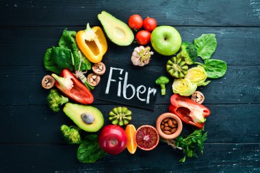 Lif içeren meyve ve sebzeler: Avokado, kivi, elma, domates, ıspanak, kırmızı biber, portakal, limon. Üst te. Metniniz için boş alan. Siyah arka planda.