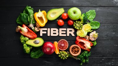 Lif içeren meyve ve sebzeler: Avokado, kivi, elma, domates, ıspanak, kırmızı biber, portakal, limon. Üst te. Metniniz için boş alan. Siyah arka planda.