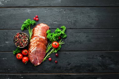 Baharat ve otlar ile dilimlenmiş füme et. Siyah ahşap bir arka plan üzerinde. Üst te. Metniniz için boş alan.