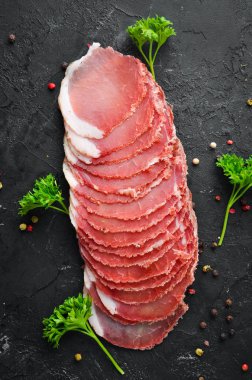 Baharat ve otlar ile dilimlenmiş füme et. Siyah ahşap bir arka plan üzerinde. Üst te. Metniniz için boş alan.