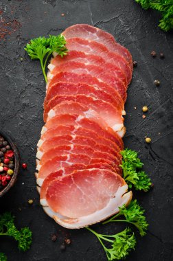 Baharat ve otlar ile dilimlenmiş füme et. Siyah ahşap bir arka plan üzerinde. Üst te. Metniniz için boş alan.