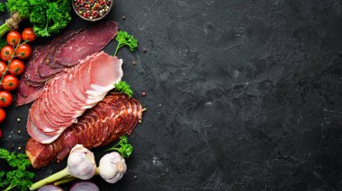 Baharat ve otlar ile dilimlenmiş füme et. Siyah ahşap bir arka plan üzerinde. Üst te. Metniniz için boş alan.