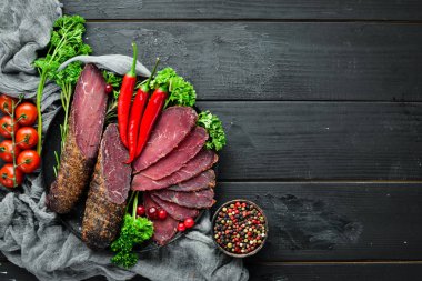 Baharat ve otlar ile kurutulmuş dana eti. Eski siyah masada biftek. Üst te. Metniniz için boş alan.