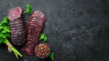 Baharat ve otlar ile kurutulmuş dana eti. Eski siyah masada biftek. Üst te. Metniniz için boş alan.