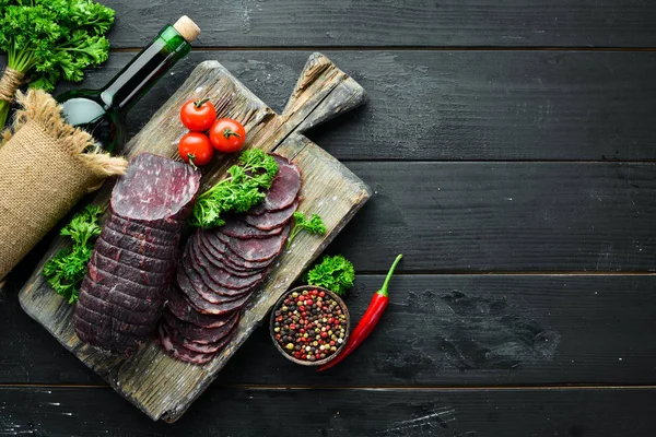 Baharat ve otlar ile kurutulmuş dana eti. Eski siyah masada biftek. Üst te. Metniniz için boş alan.