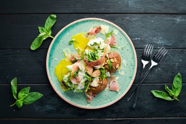 Proshutto, yumurta ve arugula ile sandviç. Kahvaltı. Tabakta. Üst te. Düz döşeme kompozisyonU Ücretsiz kopyalama alanı.