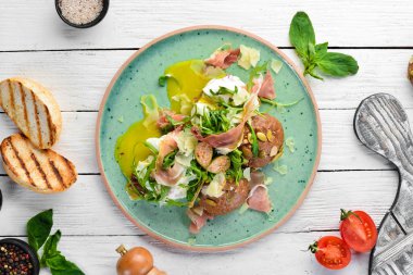 Proshutto, yumurta ve arugula ile sandviç. Kahvaltı. Tabakta. Üst te. Düz döşeme kompozisyonU Ücretsiz kopyalama alanı.